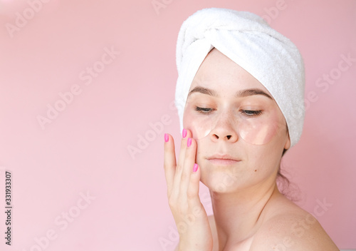 portrait of a young girl on a pink background. puts patches on your eyes . for beauty articles, beauty salon, cosmetics