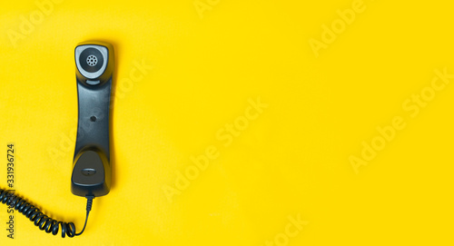 Landline telephone device on yellow background. Communication technology or cutomer support concept