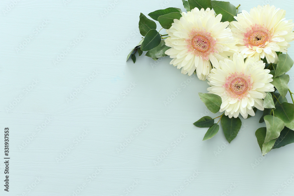 spring bouquet of white gerbera flowers over pastel wooden background. top view, flat lay
