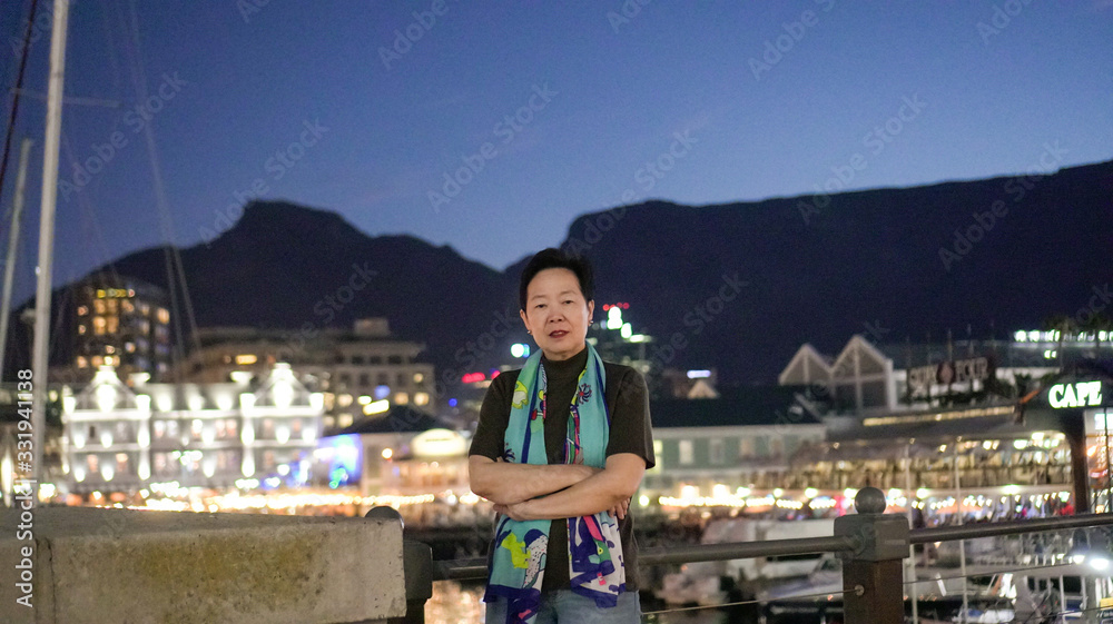 Asian senior elder travel to South Africa Cape town V and A waterfront landmark at night sunset behind table mountain scenic