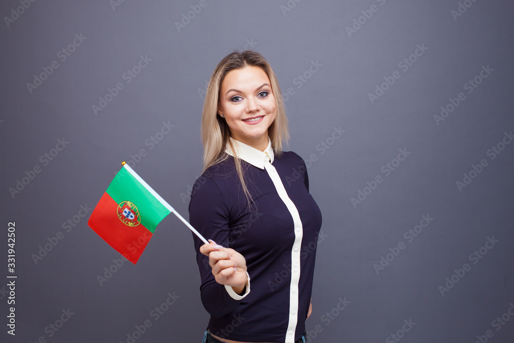 Immigration and the study of foreign languages, concept. A young smiling woman with a Portugal flag in her hand. Immigration and the study of foreign languages, concept. A young smiling woman with a Portugal flag in her hand.