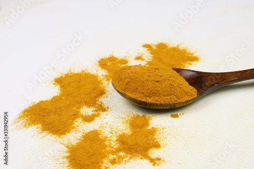 Turmeric powder in a wooden spoon isolated on a white background is an ingredient in turmeric foods and ingredients in skin care products. Turmeric helps the skin to be strong.