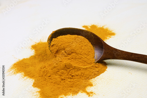 Turmeric powder in a wooden spoon isolated on a white background is an ingredient in turmeric foods and ingredients in skin care products. Turmeric helps the skin to be strong.