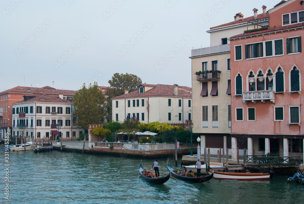 Twilight in Venice, Italy. View of the Grand Canal and houses on the shore, people ride boats.