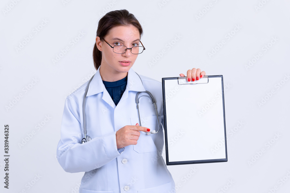 Portrait of young beautiful woman doctor showing clipboard