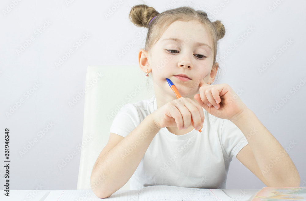 little girl of primary school at the table teaches lessons, the concept of education little girl of primary school at the table teaches lessons, the concept of education