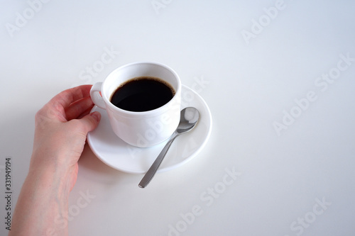 Hand holding a mug.   Set  mug  teaspoon and saucers. On white background.