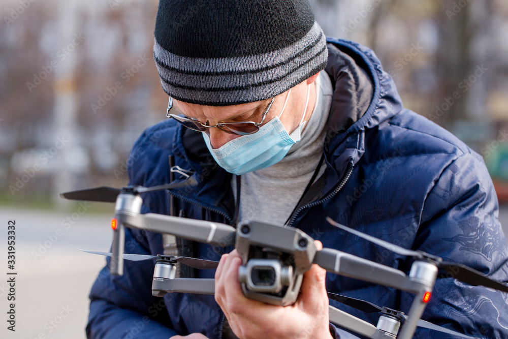 Obraz premium Surveyor in a protective mask prepares a quadcopter for flying around an object