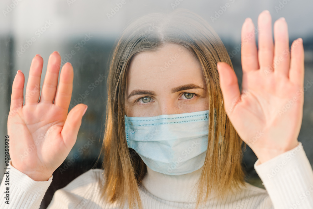 Coronavirus. Sick woman wearing protection face mask looking through the window. Patient isolated in house to prevent infection. Quarantine room at hospital. Coronavirus. Sick woman wearing protection face mask looking through the window. Patient isolated in house to prevent infection. Quarantine room at hospital.
