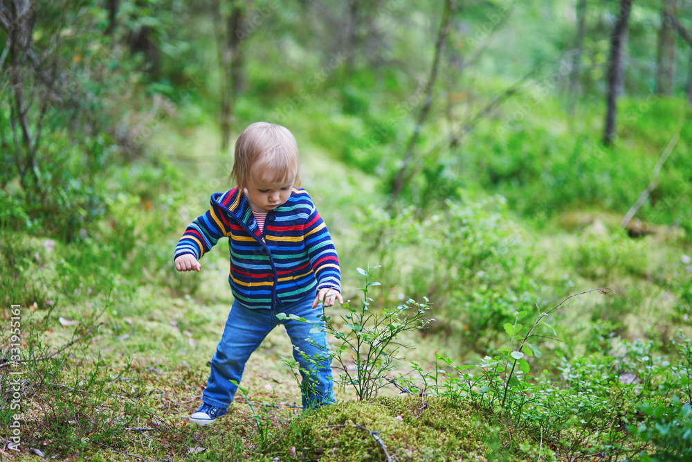 Adorable baby girl in the forest, looking at bell-flower. Little child having fun outdoors. Kid exploring nature Adorable baby girl in the forest, looking at bell-flower. Little child having fun outdoors. Kid exploring nature