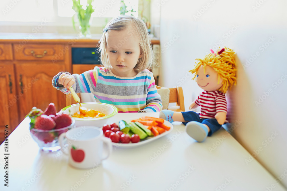 Adorable toddler girl eating fresh fruits and vegetables for lunch Adorable toddler girl eating fresh fruits and vegetables for lunch