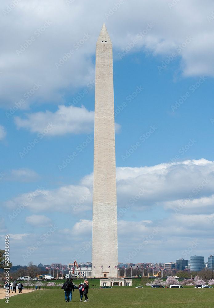 Tourists walk towards the towering Washington Monument 