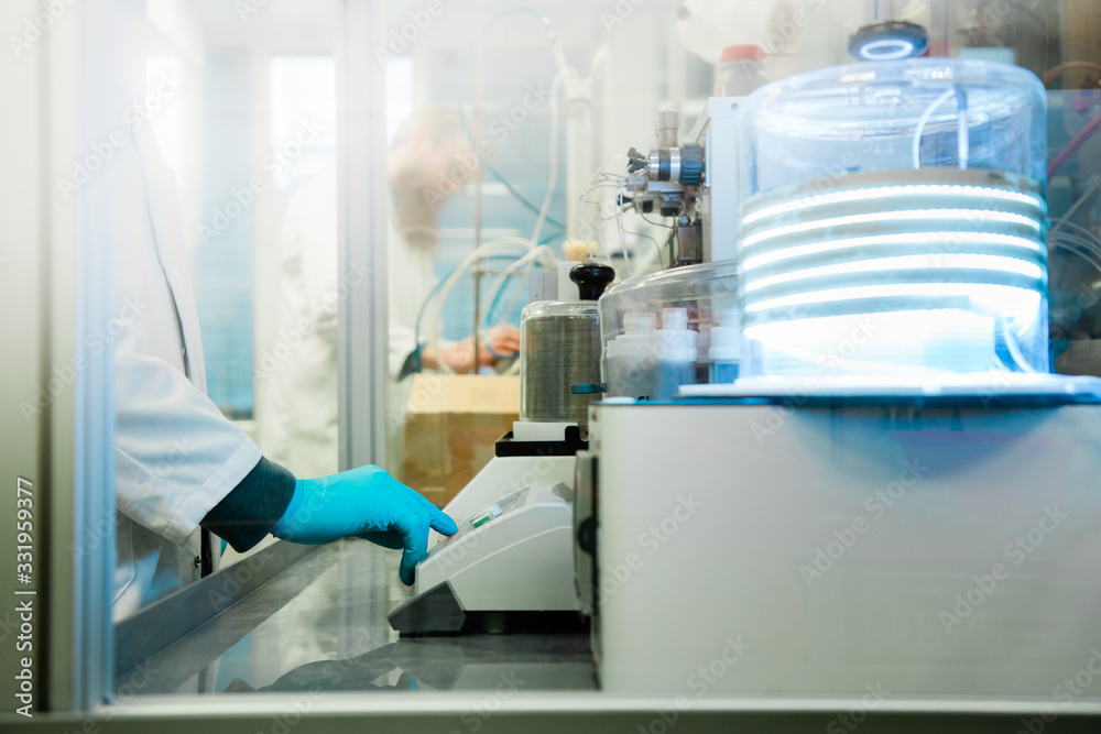 Closeup of man's hand in gloves preparing machine to perform analysis of sample suspected for coronavirus infection. Covid-19 pandemics laboratory diagnosis.