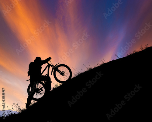 Fotografie, Obraz Cyclist pushing the bike uphill