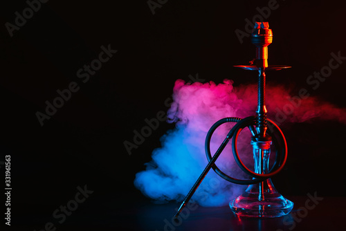 hookah with a glass flask and a metal bowl shisha with colored smoke on the table photo