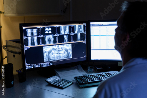 Fotografía Médecin radiologue regarde radios sur écran dans bureau sombre