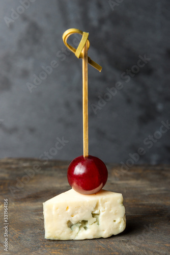 tasty canapes with cheese on a small skewer on a gray background. Vertical frame