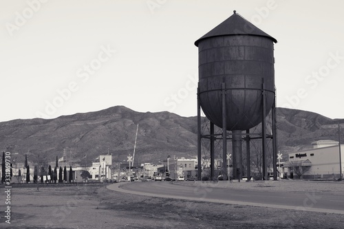 Black and white view of city, New Mexico Alamogordo at dusk with 
More details
Railroad water tower and mountains in background. 