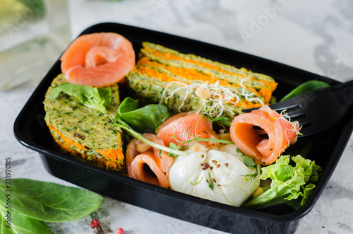 Healthy food and diet concept, restaurant dish delivery. Take away of fitness meal. Weight loss nutrition in boxes. Healthy lunch - fish, poached egg and carrot cake.