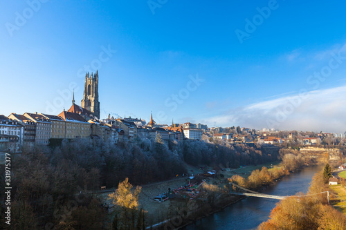 Beautiful panorama view of Fribourg (Freiburg) old town on a sunny winter day from Zaehringen Bridge with the tower of Fribourg Cathedral and Sarine River flowing below, Switzerland