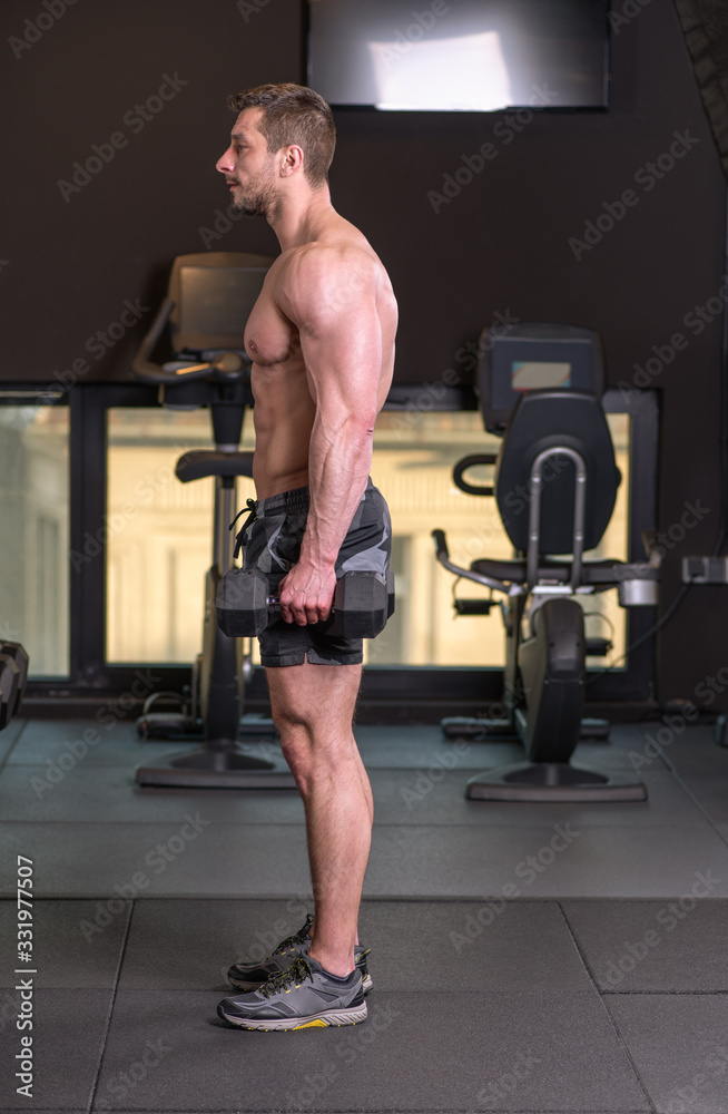 Fototapeta premium Sexy muscular man doind biceps exercise and looking at the mirror