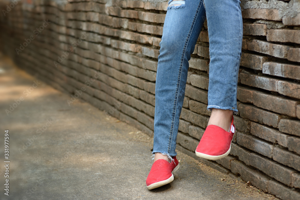 Young girl wearing ripped jeans and red shoes Young girl wearing ripped jeans and red shoes