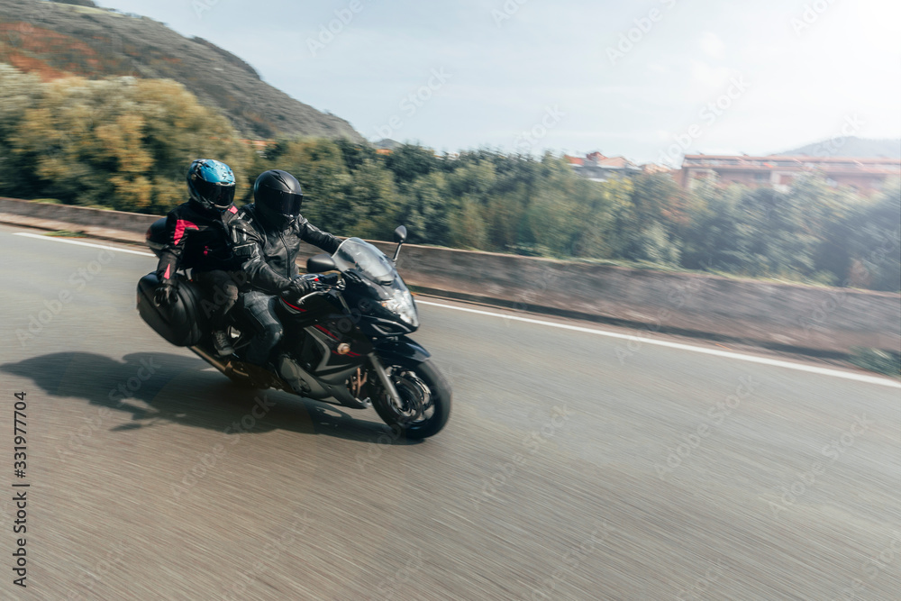 Unknown biker couple traveling by road on motorcycle
