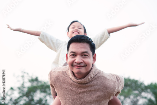 Portrait of asian father carrying his daughter on his back