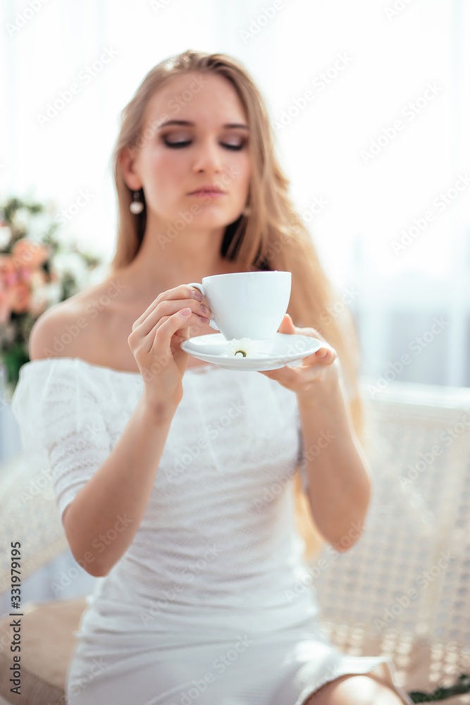 The girl drinks morning tea and enjoys life, admiring a bouquet of flowers . The girl drinks morning tea and enjoys life, admiring a bouquet of flowers .