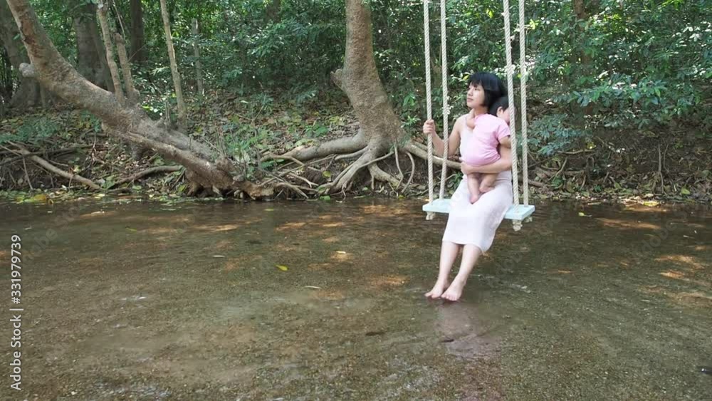 Beautiful asian woman or mother and asian cute baby infant girl or daughter admire nature while swinging back and forth. Beautiful asian woman or mother and asian cute baby infant girl or daughter admire nature while swinging back and forth.