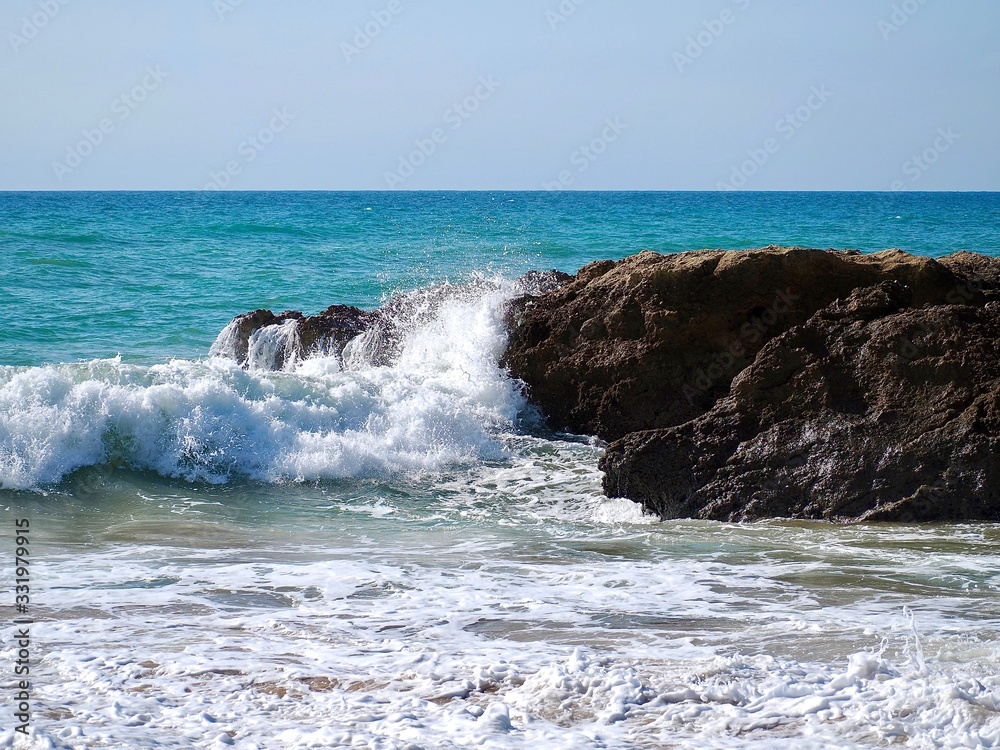 Nature photo of rocks with waves in blue ocean