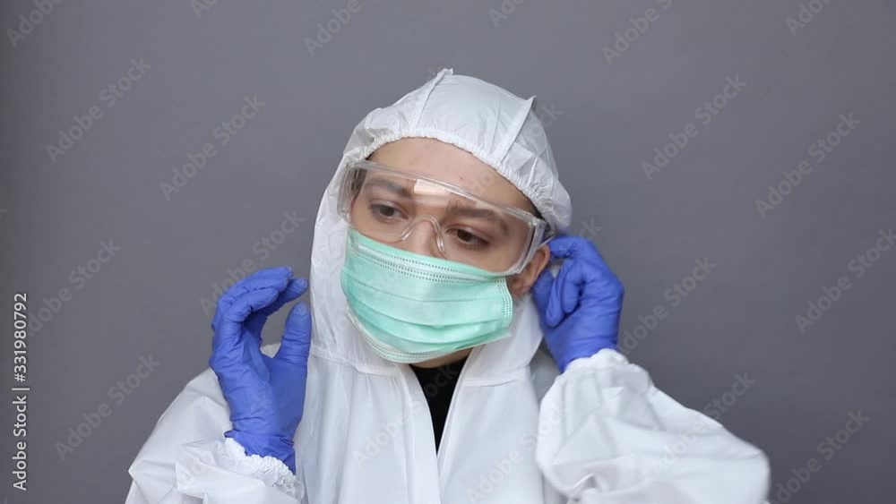 Doctor in protective costume puts on a mask Doctor in protective costume puts on a mask