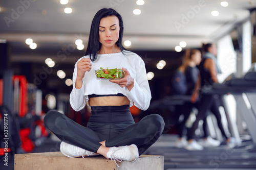 Fototapeta Naklejka Na Ścianę i Meble -  Beautiful sport woman in sportswear eating salad in gym.