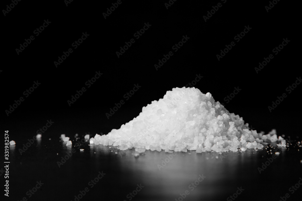A handful of coarse white salt on a black table