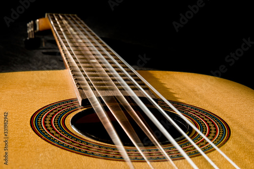 Classical guitar with vibrating strings on a black   background