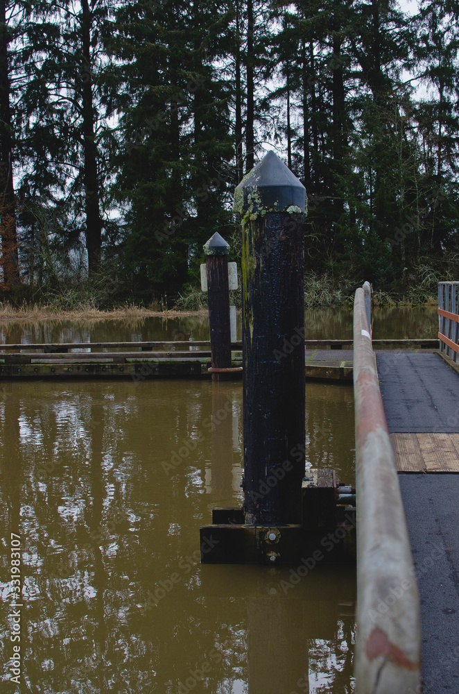 Φωτογραφία The green post on the dock walkway along the river banks in the coastline back are of oregon