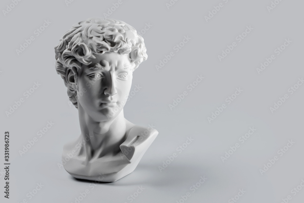 Gypsum statue of David's head. Michelangelo's David statue plaster copy on grey background with copyspace for text. Ancient greek sculpture, statue of hero