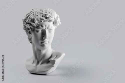 Gypsum statue of David's head. Michelangelo's David statue plaster copy on grey background with copyspace for text. Ancient greek sculpture, statue of hero photo