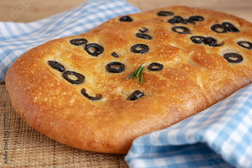 Close up view to bread with olives on the table with kitchen blue towels.