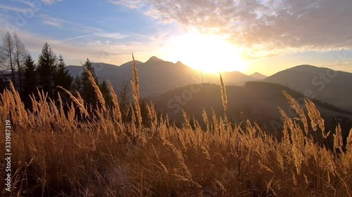 Peaceful sunrise over mountains landscape and dry grass