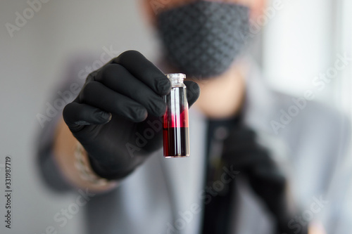 Young man holding test tubes with blood and antidote in his hand. photo