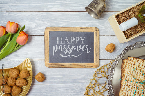 Jewish holiday Passover background with matzo, seder plate, wine and chalkboard frame on wooden table.
