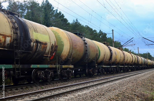 Freight train with petroleum tank cars on railroad. Rail cars carry oil and ethanol. Railway logistics explosive cargo. Transportation of methanol, crude and gas.Petrochemical tank cars