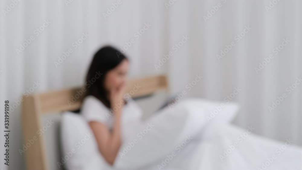 Blur scene of beautiful Asian woman use tablet on bed and look sleepy by yawning then lie on white bed. Blur scene of beautiful Asian woman use tablet on bed and look sleepy by yawning then lie on white bed.