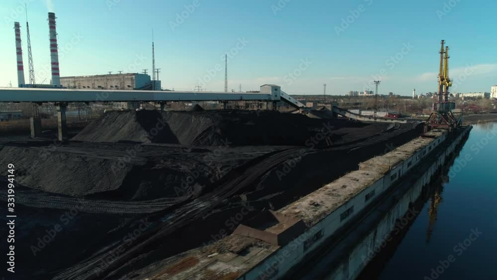 Aerial view of open coal warehouse near river with crane and conveyor, CHP plant background Aerial view of open coal warehouse near river with crane and conveyor, CHP plant background