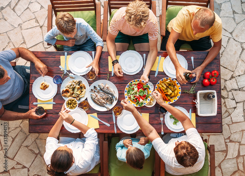 Big multigenerational family dinner in process. Top view image on table with food and hands. Food consumption and multigenerational family concept image.