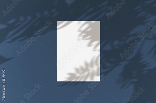 Blank white vertical paper sheet 5x7 inches with palm shadow overlay. Modern and stylish greeting card or wedding invitation mock up.