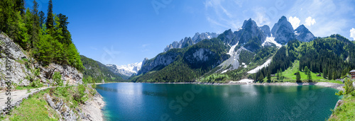 Famous Lake Gosau and Gosaukamm with Mount Dachstein. Spring is here! The snow is melting and spring brings the luscious green back to nature. The sun is about to hide behind the high peaks.