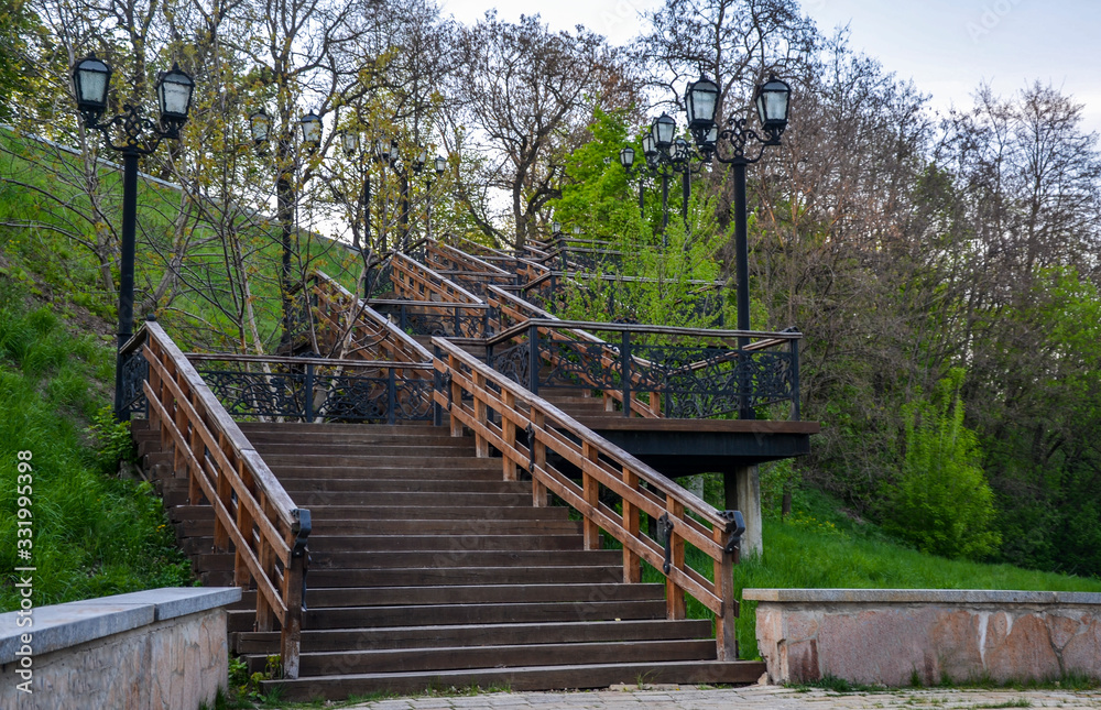 Wooden staircase with vintage lanterns in the summer city park. Chernihiv, Ukraine. Tourist destination, landmark