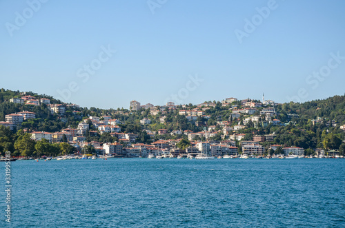 Hillside waterfront houses of the residential area at the Bosphorus Strait. Near the shore there are boats. Istanbul, Turkey.